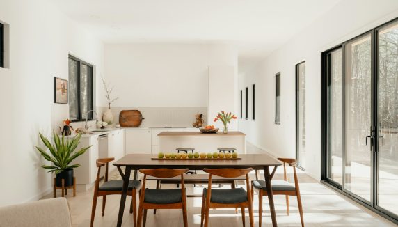 Modern dining room with table, chairs, and kitchen.