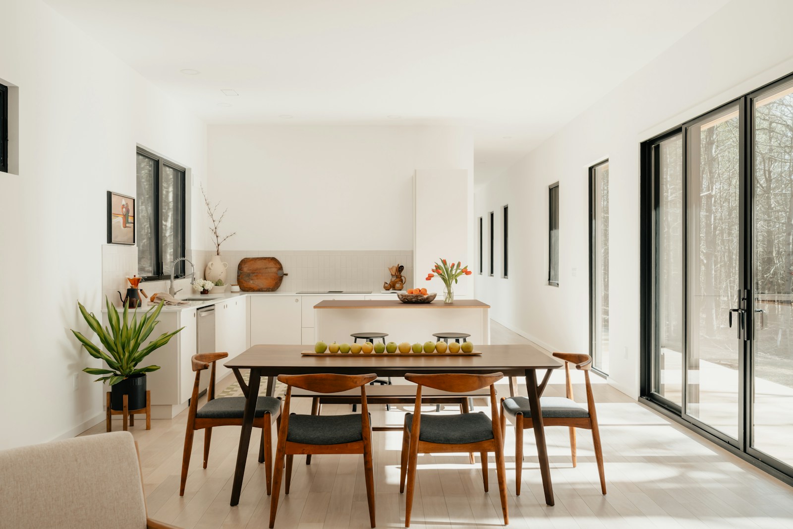 Modern dining room with table, chairs, and kitchen.