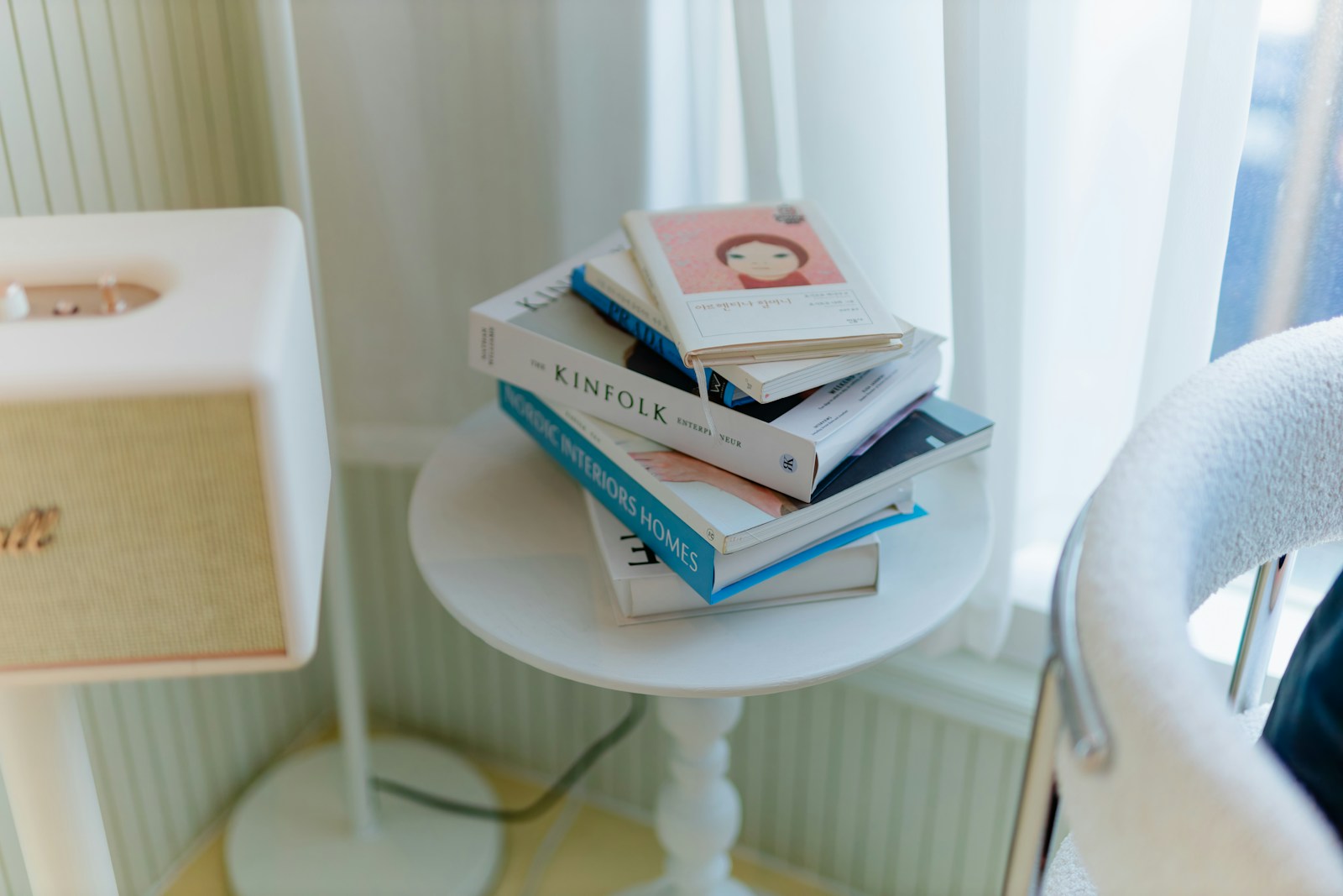 Books are stacked on a small white table.
